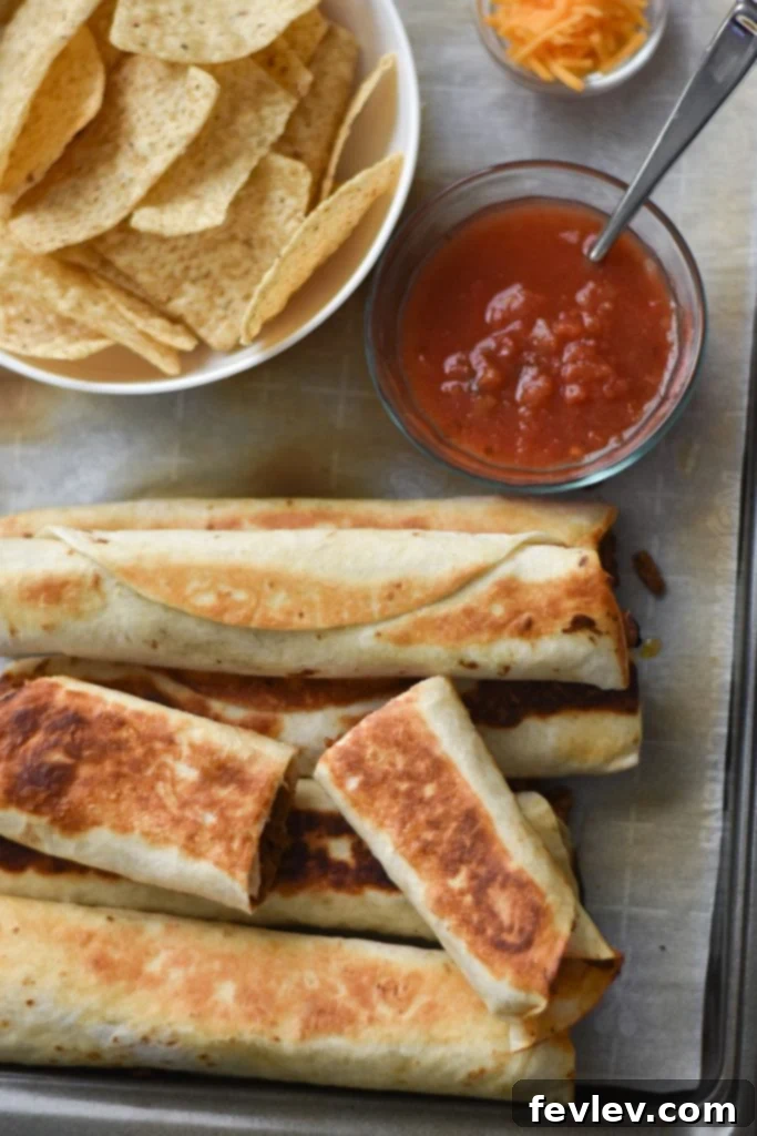 Golden brown crispy beef taquitos, perfectly pan-fried and ready to serve on a rustic wooden board.