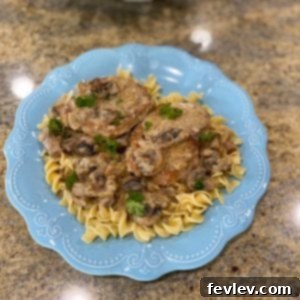 Perfectly seared pork chops coated in a rich, creamy mushroom sauce, garnished with fresh herbs.
