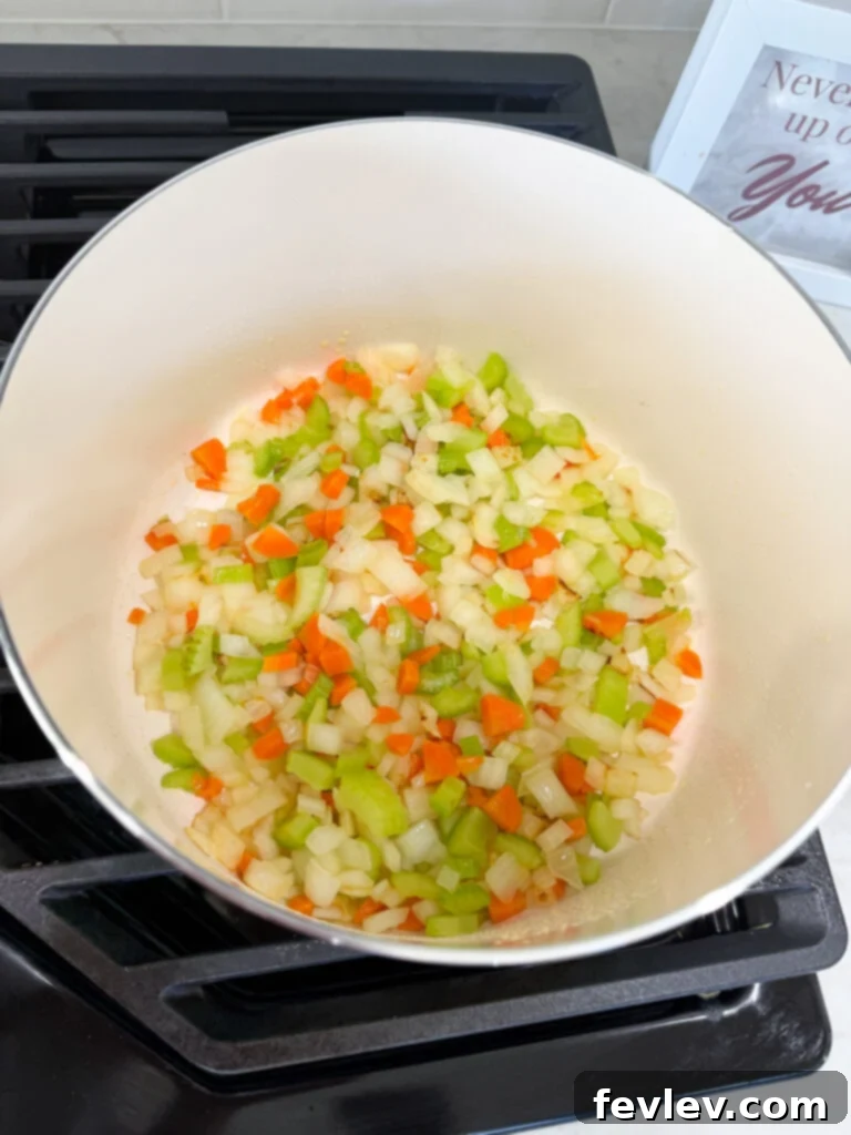 Finely diced onion, celery, and carrots sautéing in olive oil in a Dutch oven, forming the aromatic base for the Bolognese.