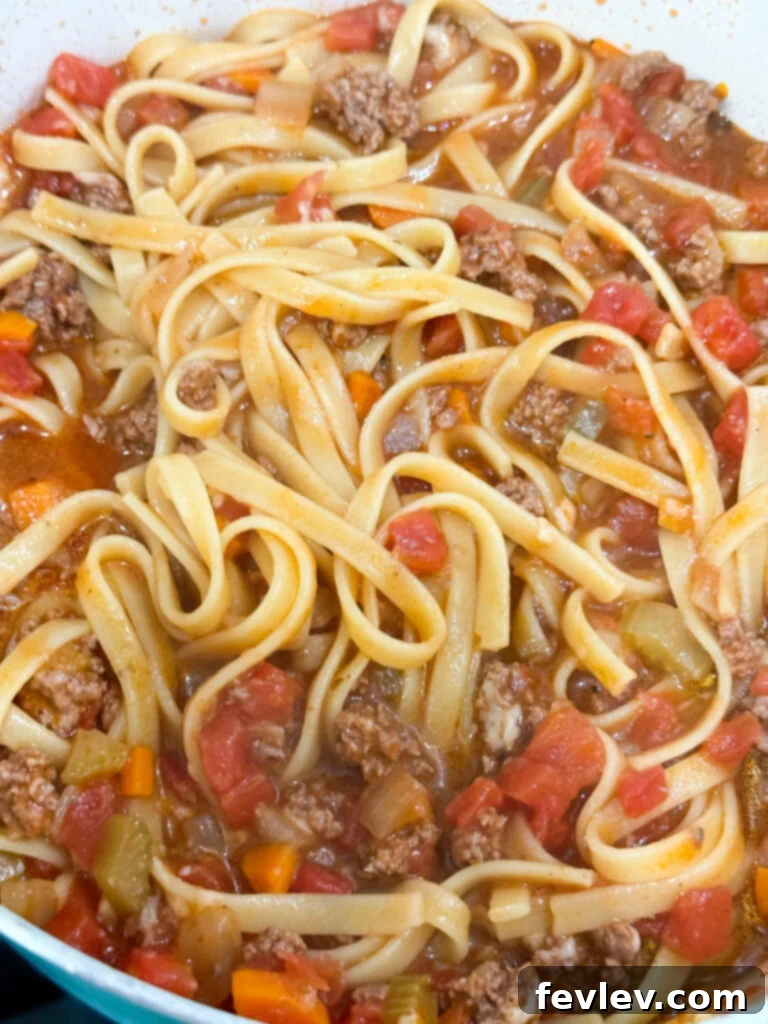Finished One-Pot Beef Bolognese stirred with Parmesan cheese, ready to be served from the pot.