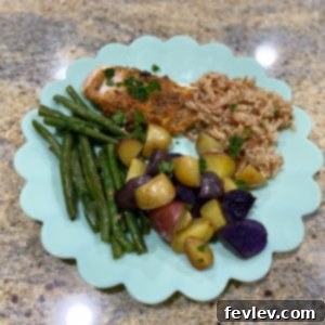 Crispy herb-crusted chicken breasts with roasted baby potatoes and fresh green beans, artfully arranged on a single sheet pan, ready to serve as a complete meal.