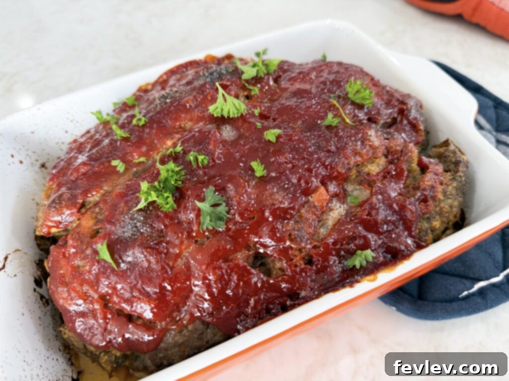 Shaping meatloaf mixture in the loaf pan and spreading glaze over it.