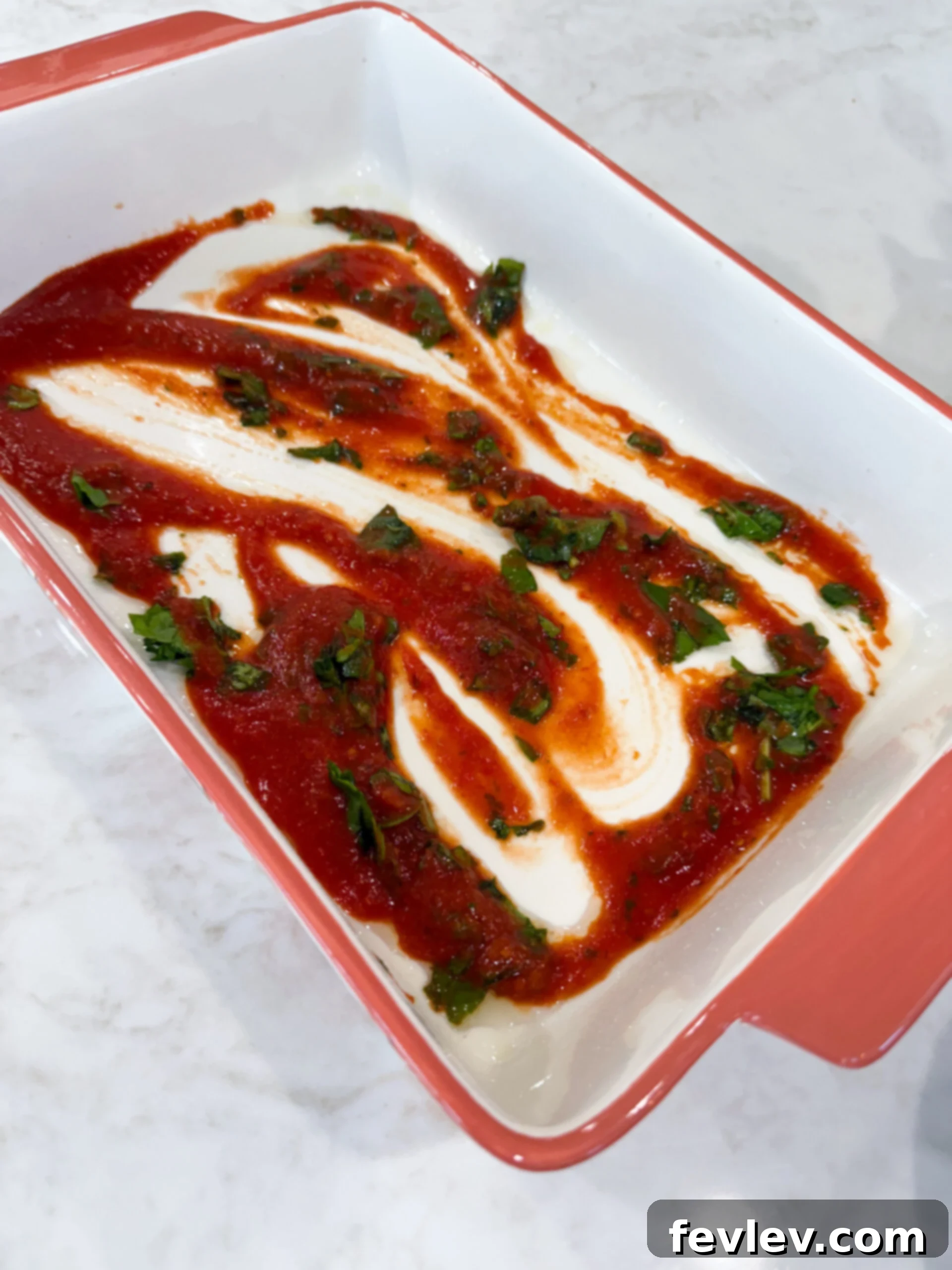 Marinara sauce and spinach spread on the bottom of a baking dish, forming the first flavorful layer.