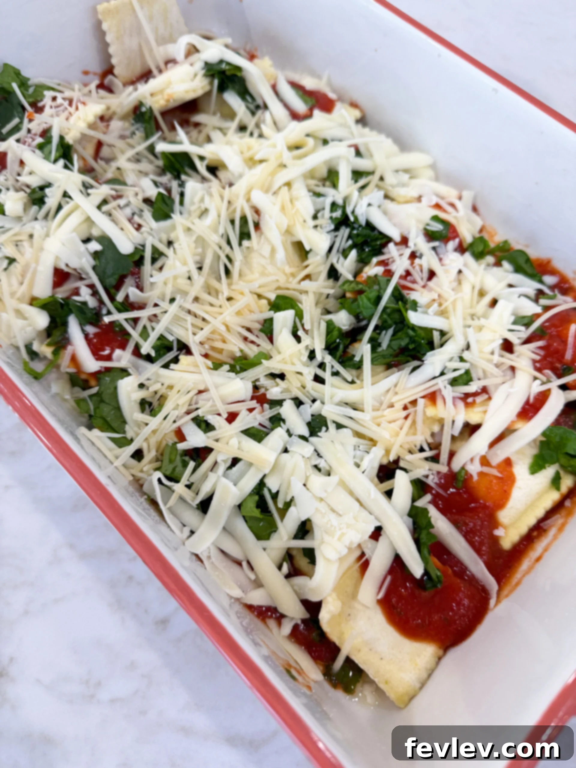 Carefully layering ravioli, marinara sauce, and cheeses in a baking dish to create a comforting baked dinner.