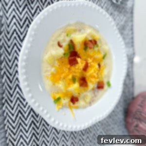 Delicious bowl of creamy Classic Loaded Potato Soup topped with bacon, cheddar, and green onions