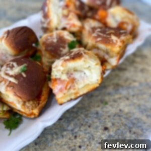 Delicious Chicken Parmesan Sliders with melted provolone and mozzarella cheese, marinara sauce, and herbs on toasted Hawaiian rolls.