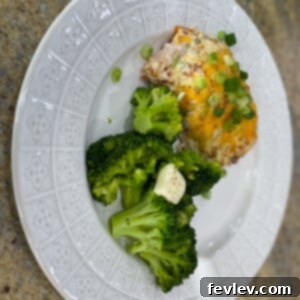 Delicious and cheesy Crack Chicken Bake garnished with fresh green onions, served in a white baking dish.