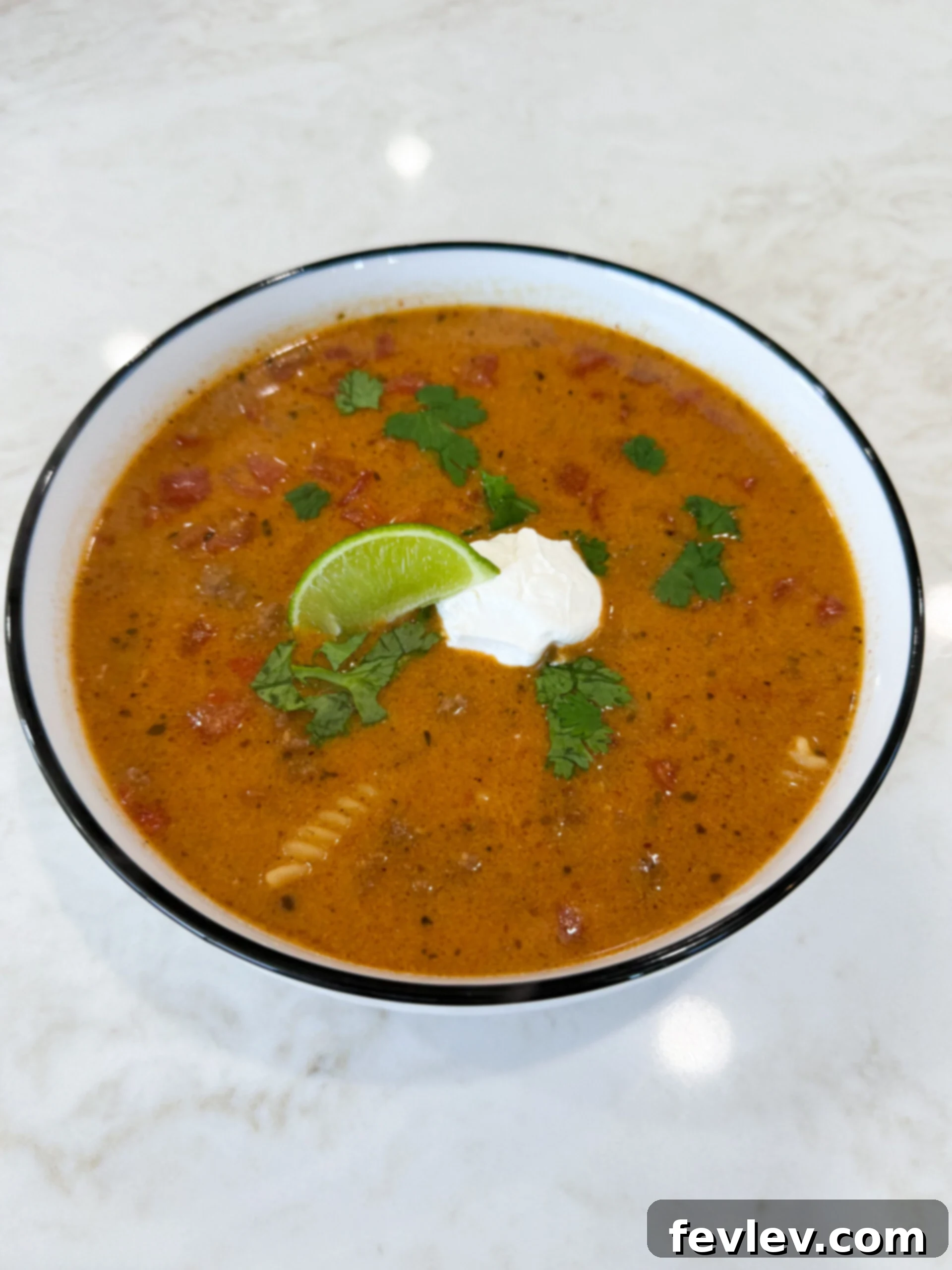Golden Queso Chili 2 Bowl of cheesy queso chili topped with sour cream, lime, and cilantro, ready to be enjoyed