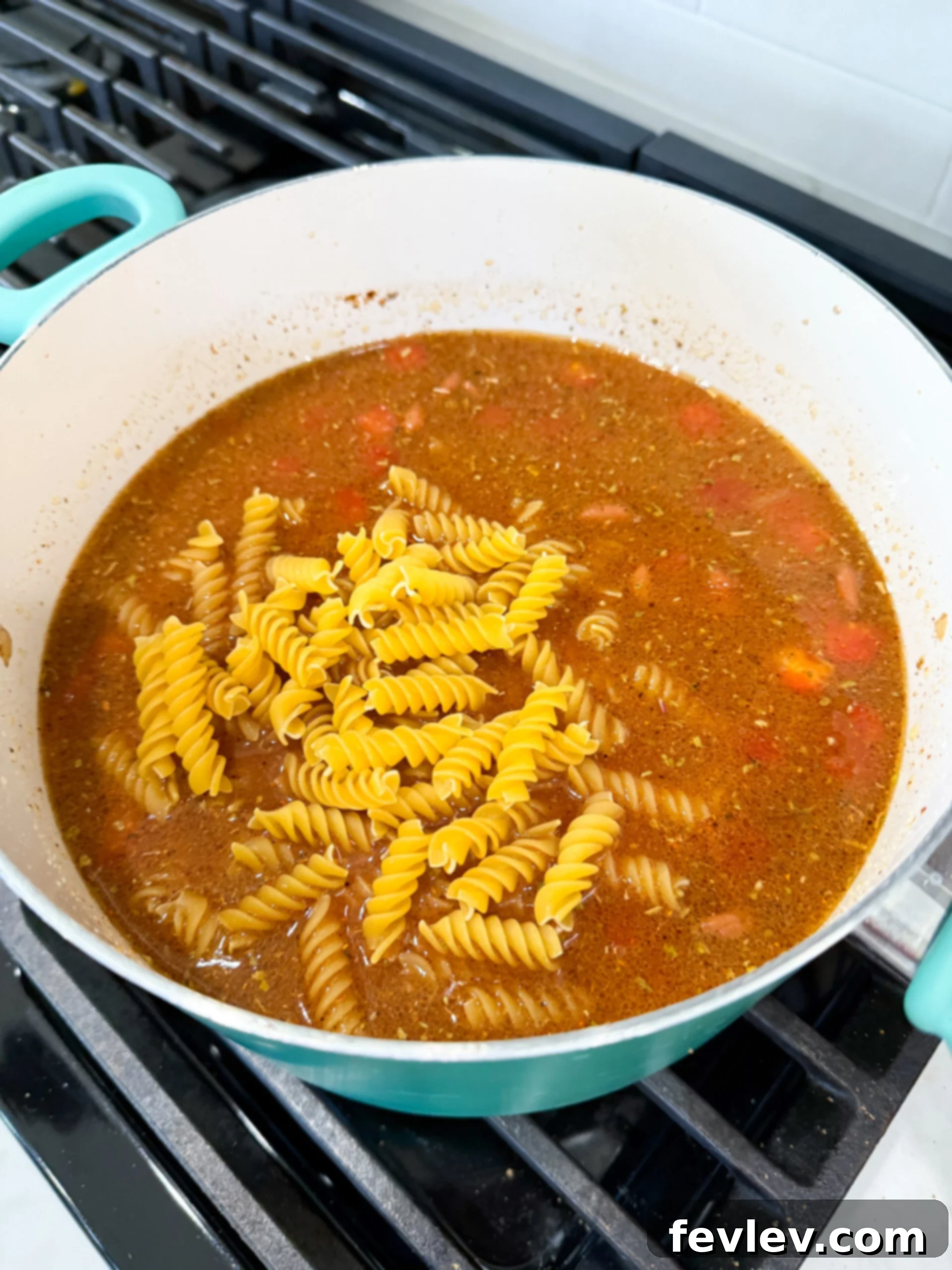 Golden Queso Chili 7 All chili ingredients, including beef broth, beans, tomatoes, tomato soup, and spices, combined in a pot before simmering